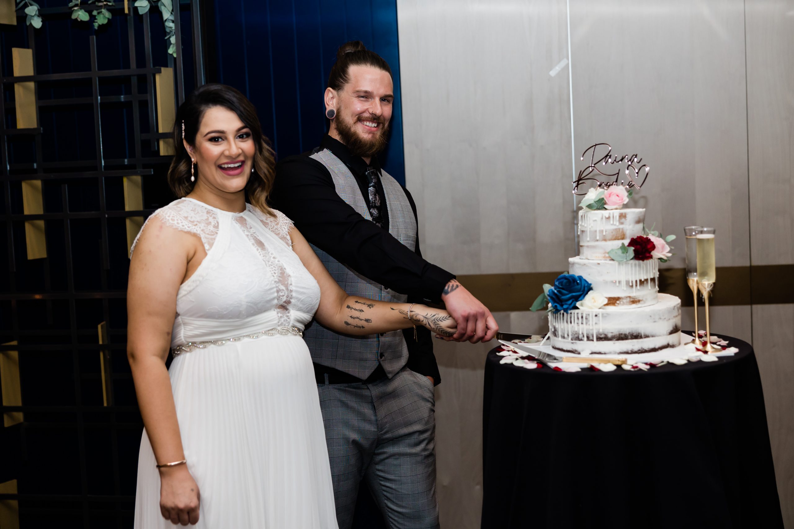 A bride and groom smiling while cutting a cake together